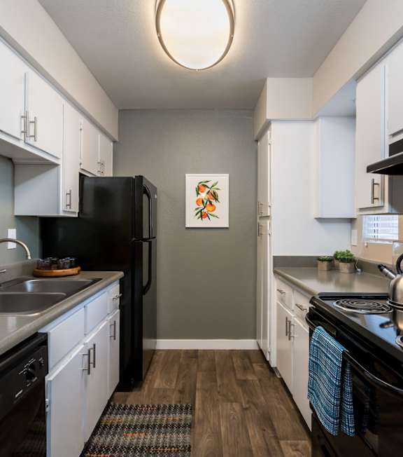 A kitchen with black appliances and white cabinets.