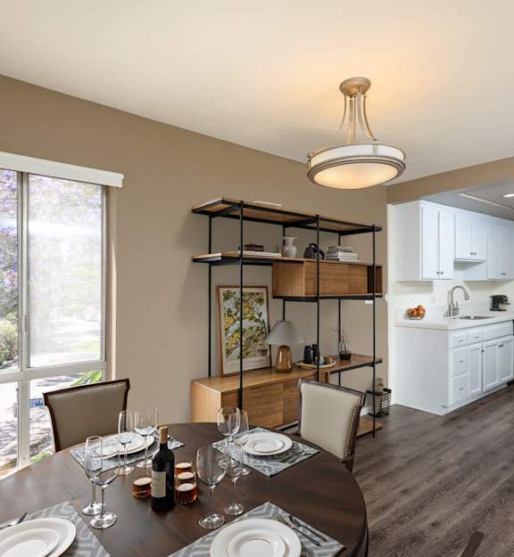 A dining room with a table set for two with a view of a backyard.