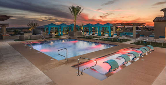 A pool surrounded by palm trees and a building.