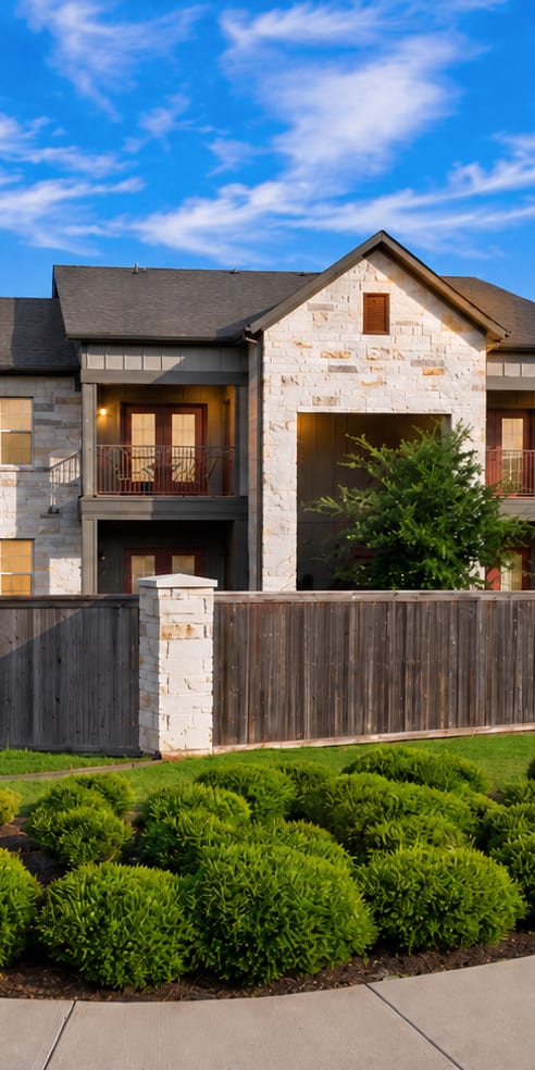 A large, modern house with a stone facade and a wooden fence.