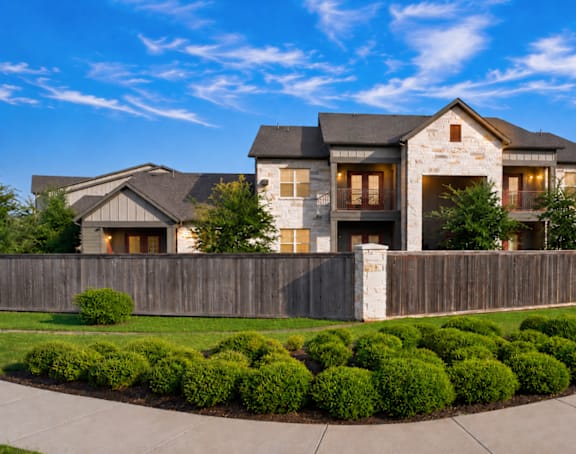 A large, modern house with a stone facade and a wooden fence.