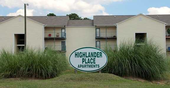 The sign in front of the building says Highlander Place Apartments.