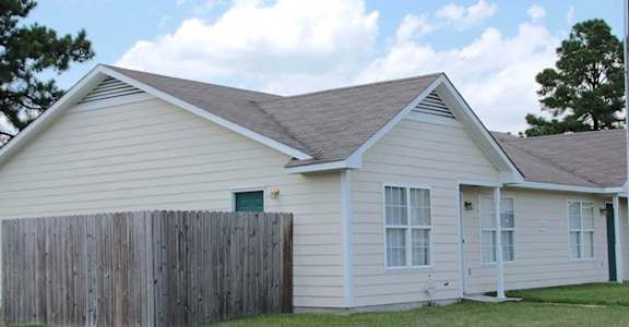 A house with a grey roof and a wooden fence.