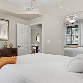 A bedroom with a large bed, a dresser, and a mirror.