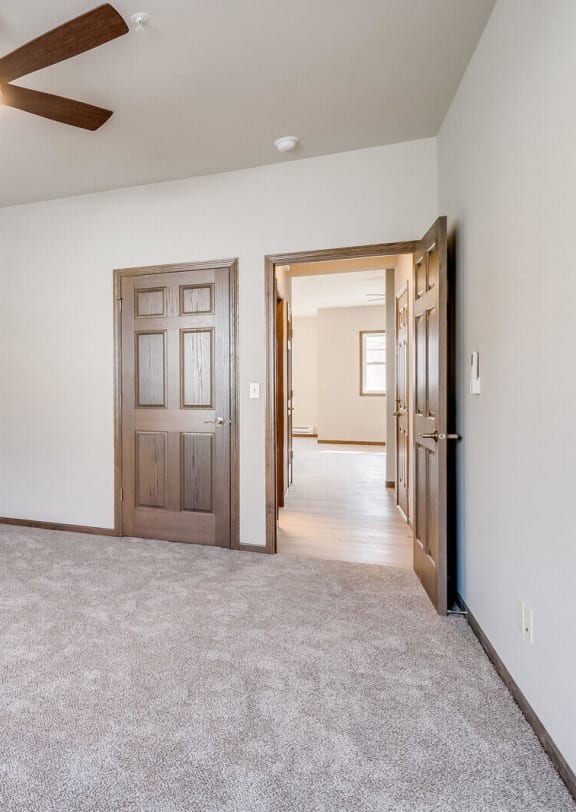 a bedroom with white walls and a ceiling fan