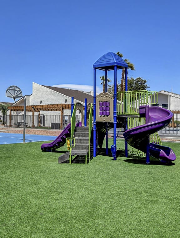 a courtyard with a playground and yellow chairs in front of an apartment building