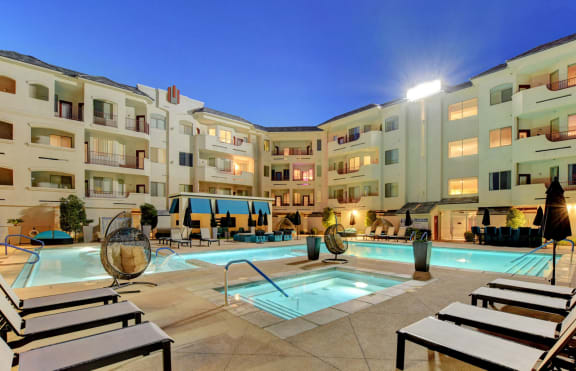 a pool with lounge chairs and umbrellas in front of a building at The Lennox, Las Vegas
