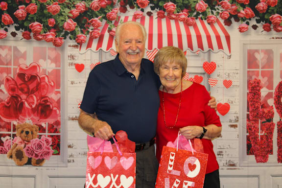 A man and woman holding red bags with the word "love" on them.