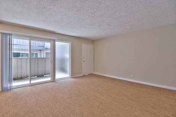 A room with a carpeted floor and a window with blinds.