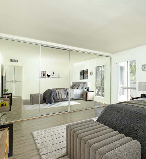 A bedroom with a large bed and a mirrored wall.