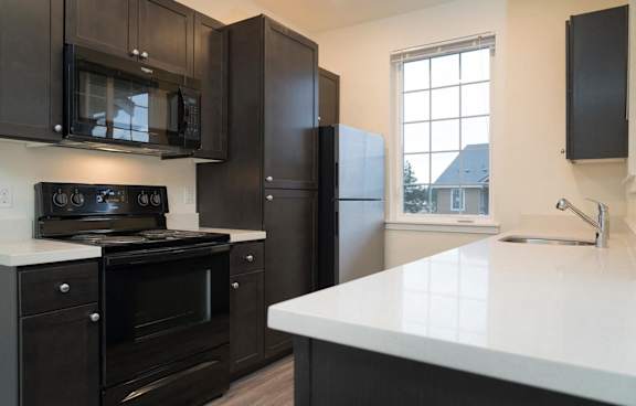 A kitchen with black cabinets and a white countertop.