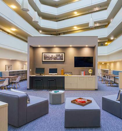 A modern office space with a central desk, chairs, and a television.