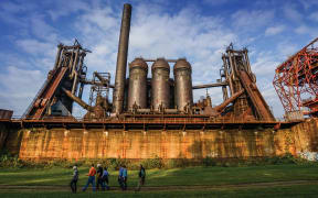 people walking in front of an old factory