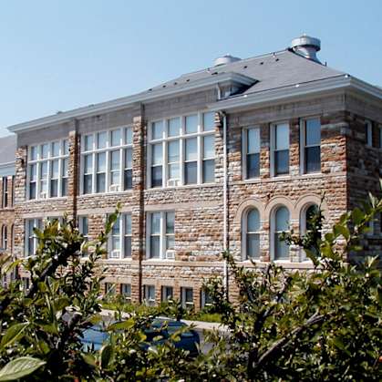 A large building with a grey roof and a stone facade with arched windows.