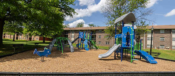 A playground with a blue slide and a green tree.