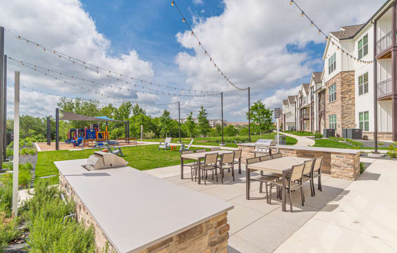 A patio with tables and chairs is surrounded by a grassy area and buildings. at Crossroad Commons, Texas, 78653