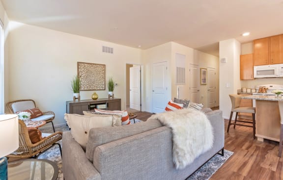 A living room with a grey couch and a white fur throw. at Stonepointe 55+ Apartments, Georgia