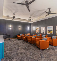 a waiting room with orange chairs and a counter and ceiling fans