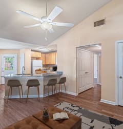 a living room with a kitchen and a ceiling fan