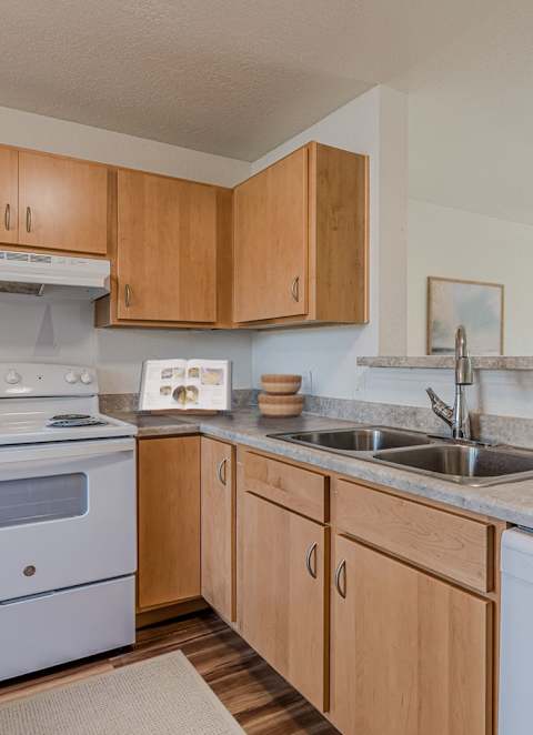 A kitchen with wooden cabinets and a white stove top oven.