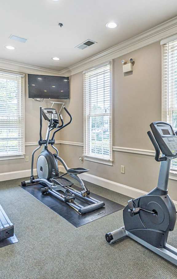 A home gym with a treadmill, elliptical trainer, and stationary bike.