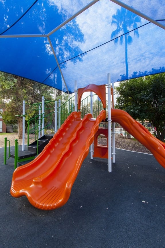 a playground with an orange slide and a blue canopy