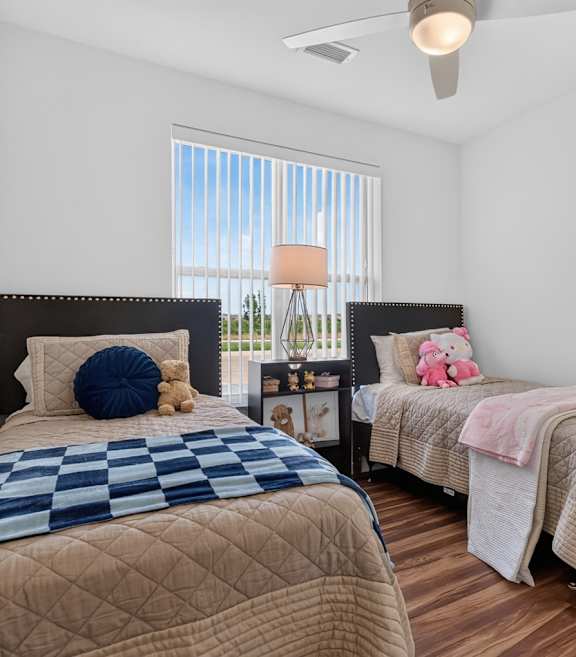 Two twin beds with blue and beige comforters in a room with white walls.