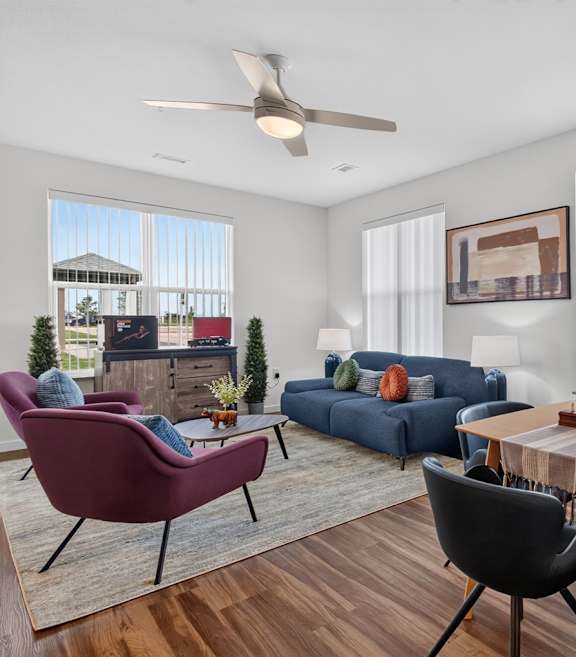 A living room with a red chair, a blue couch, and a wooden dining table.