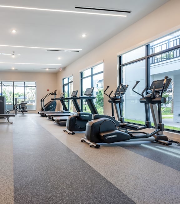 A spacious gym with a variety of equipment including treadmills, elliptical machines, and weight machines.