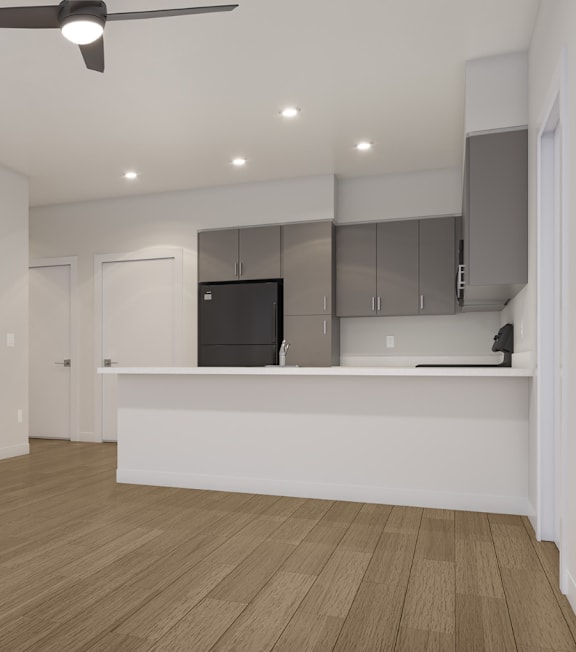 A room with a ceiling fan and a counter with cabinets.
