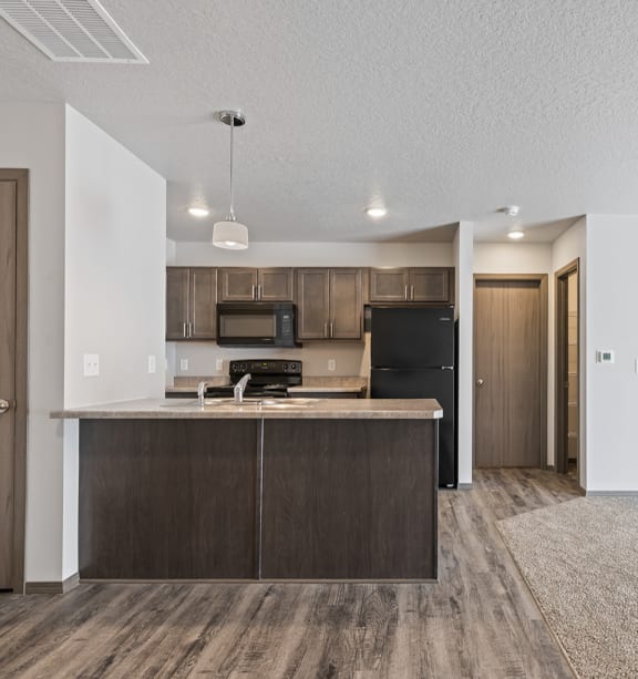 an empty living room with a kitchen and stairs