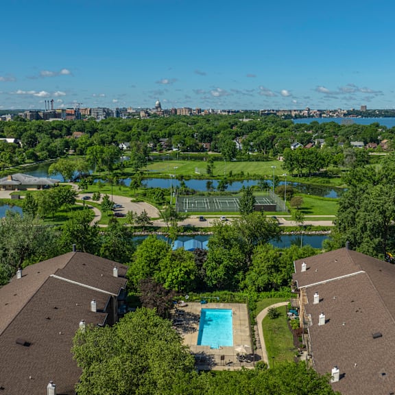 A bird's eye view of a residential area with houses, a swimming pool, and a lake.