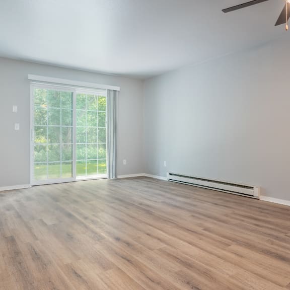 A room with wooden flooring and a sliding glass door leading to a balcony.