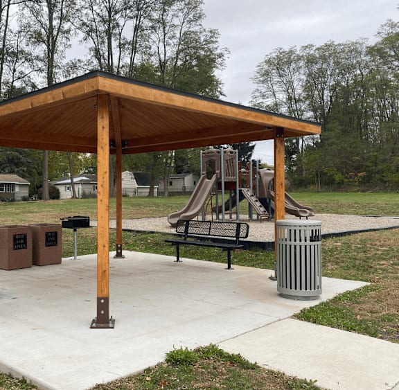 A wooden pavilion with a playground in the background.