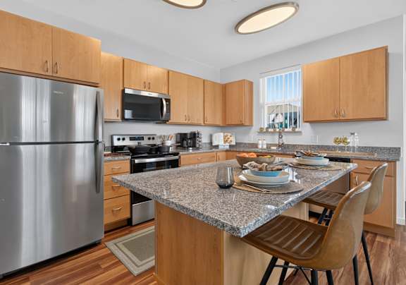 A modern kitchen with a granite countertop and wooden cabinets.