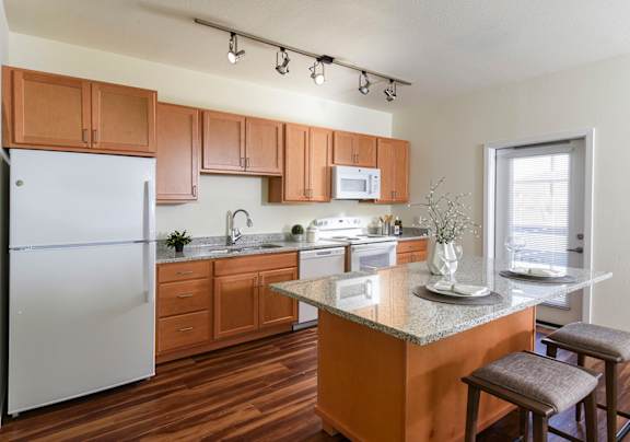 A modern kitchen with a granite countertop and wooden cabinets.