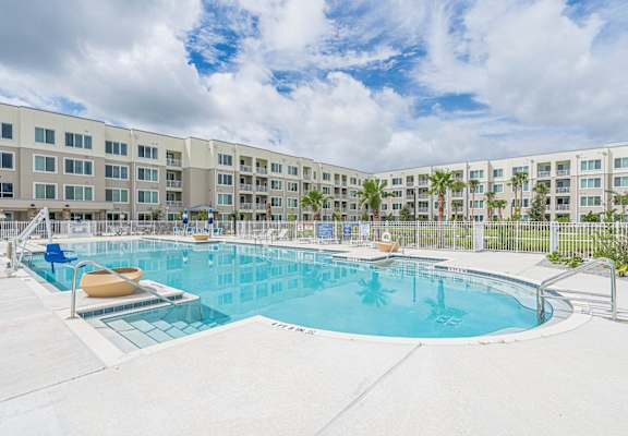 a large swimming pool with an apartment building in the backgroundat Heron Ridge 62+ Apartments, Kissimmee, Florida