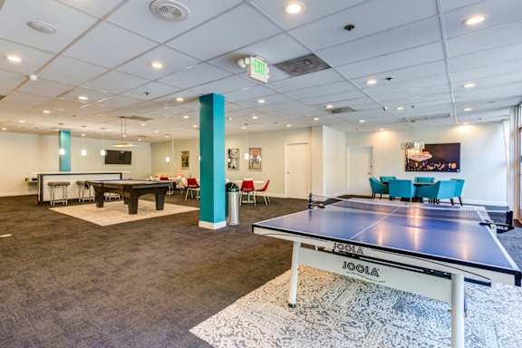 A room with a table tennis table and chairs.