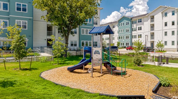 a playground with a swing set in front of an apartment building