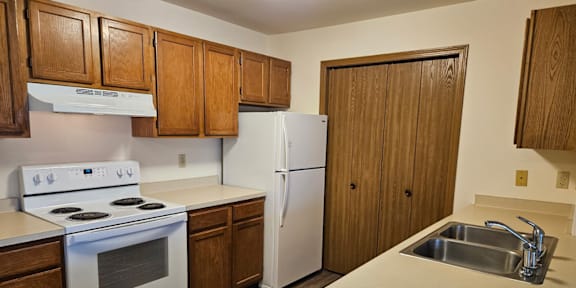 A kitchen with wooden cabinets and a white fridge.