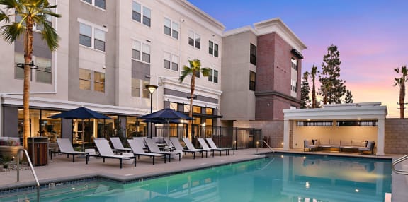 a swimming pool with lounge chairs and umbrellas in front of a hotel
