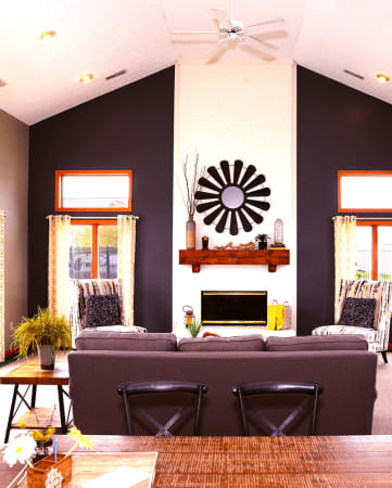 a living room with black walls and a white fireplace with a black and white mirror on the