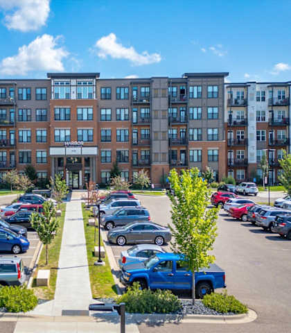 A parking lot in front of a multi-story apartment building.