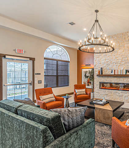 a living room with chairs and a fireplace and a chandelier