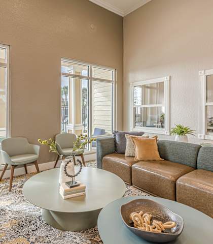A living room with a couch, chairs, and a coffee table with a bowl of pretzels on it.