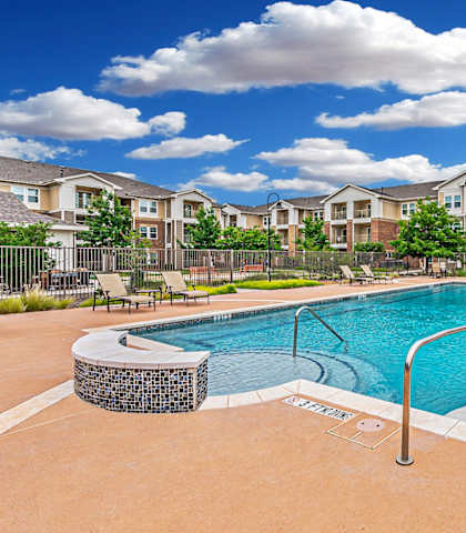 a swimming pool with an apartment building in the background at Mariposa at Spring Hollow Saginaw 55+ Apartments, Saginaw Texas