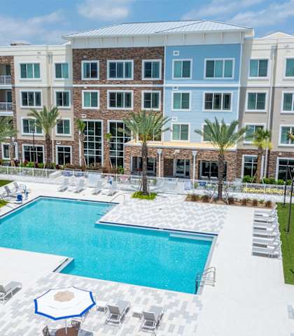 a large swimming pool in front of an apartment building at Osprey Park 62+ Apartments, Kissimmee, FL