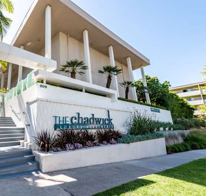 A white building with a sign that says "The Chadwick" in front of it.