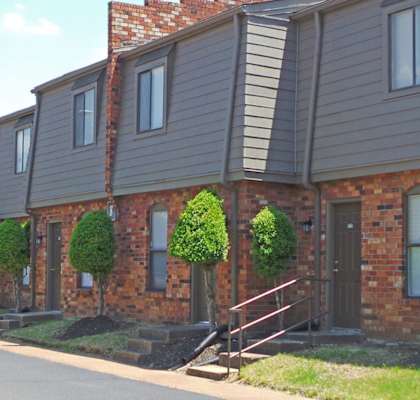 A long row of houses with green bushes in front of them.