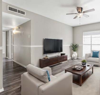 A living room with a white couch, a wooden coffee table, and a flat screen TV.